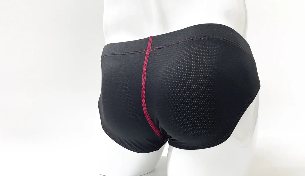 Black micro-perforated pouch briefs on a white mannequin, featuring contrast red stitching along the center back seam.