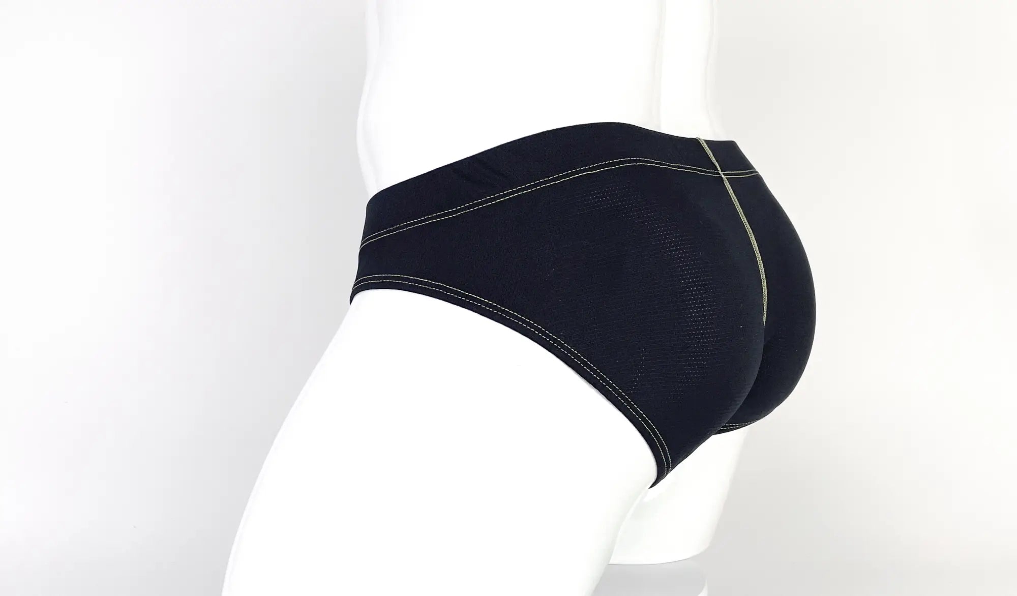Black pouch brief on a mannequin, featuring a textured mesh fabric and prominent yellow contrast stitching.