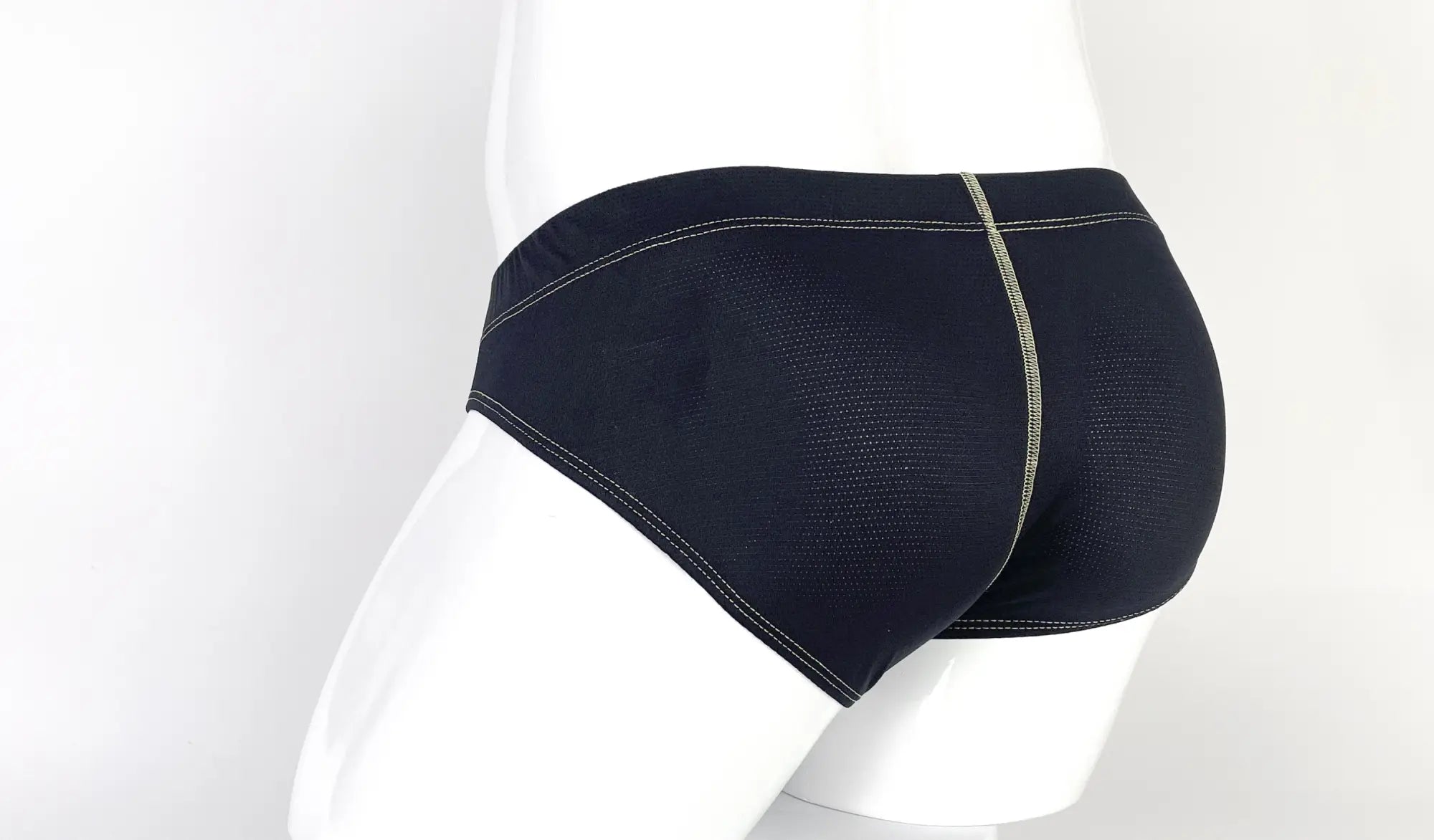 Black textured pouch brief worn on a mannequin, featuring prominent yellow contrast stitching and back seam detail.
