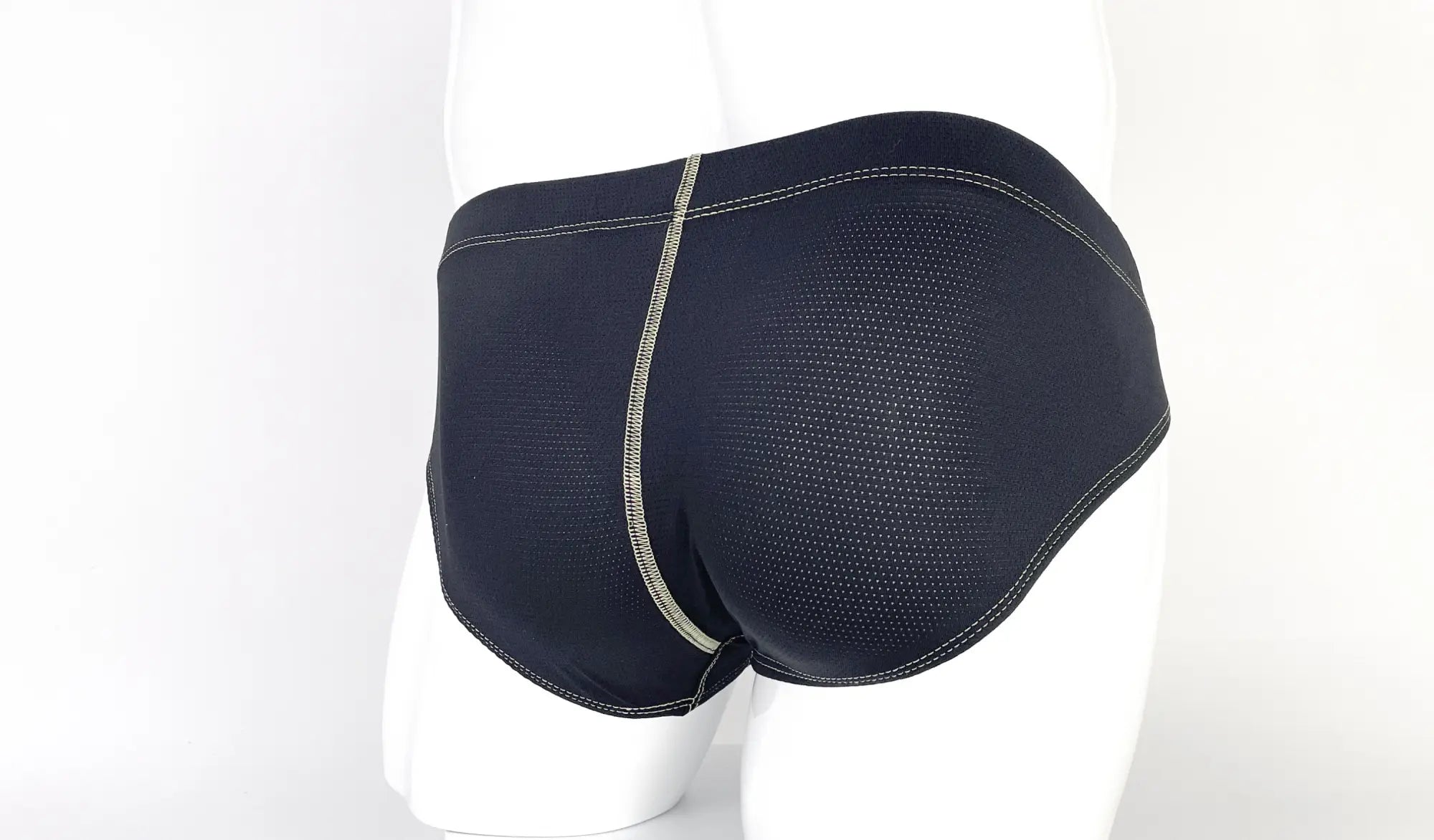 Back view of black, perforated fabric pouch briefs featuring prominent, light-colored decorative stitching.