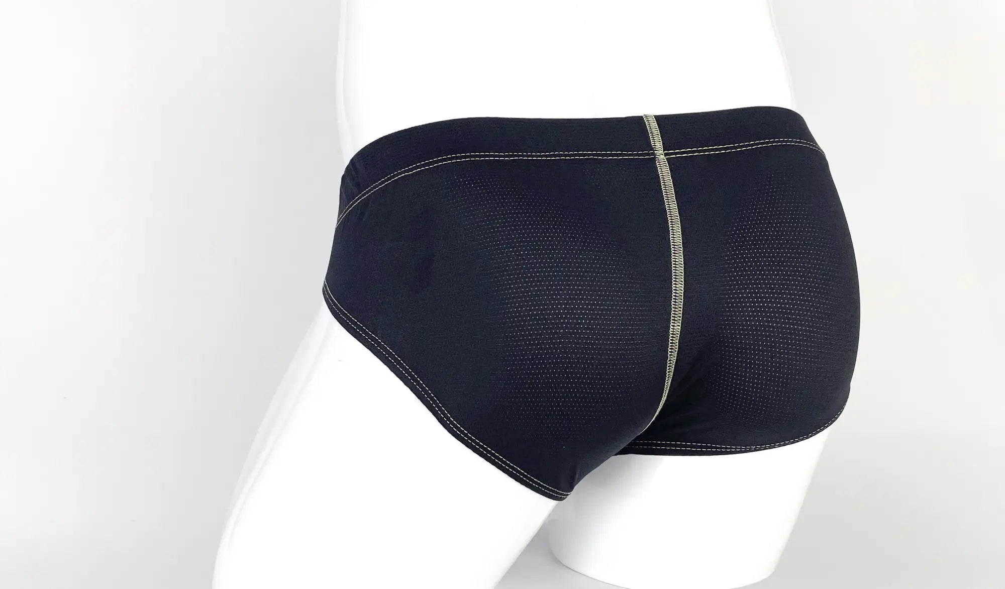 Black, perforated fabric pouch briefs with yellow contrast stitching on a white mannequin.