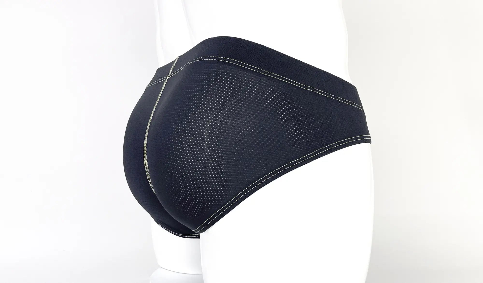 Black mesh pouch briefs featuring prominent light-colored decorative stitching detail worn on a white mannequin.