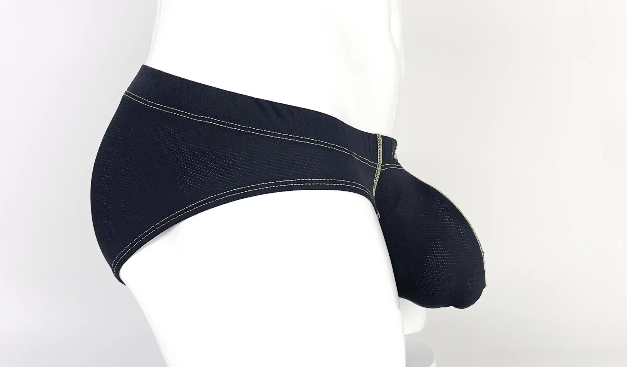Side view of a black, mesh-textured pouch brief with yellow contrast stitching on a white mannequin.