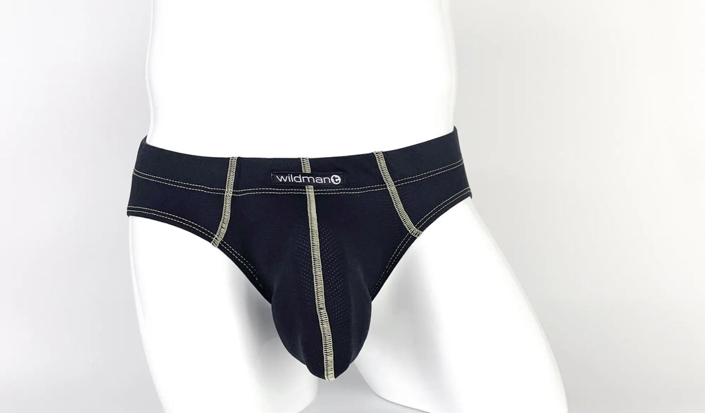 Black pouch brief with visible tan contrast stitching, center seam, and a "wildman" logo tag on a white mannequin.