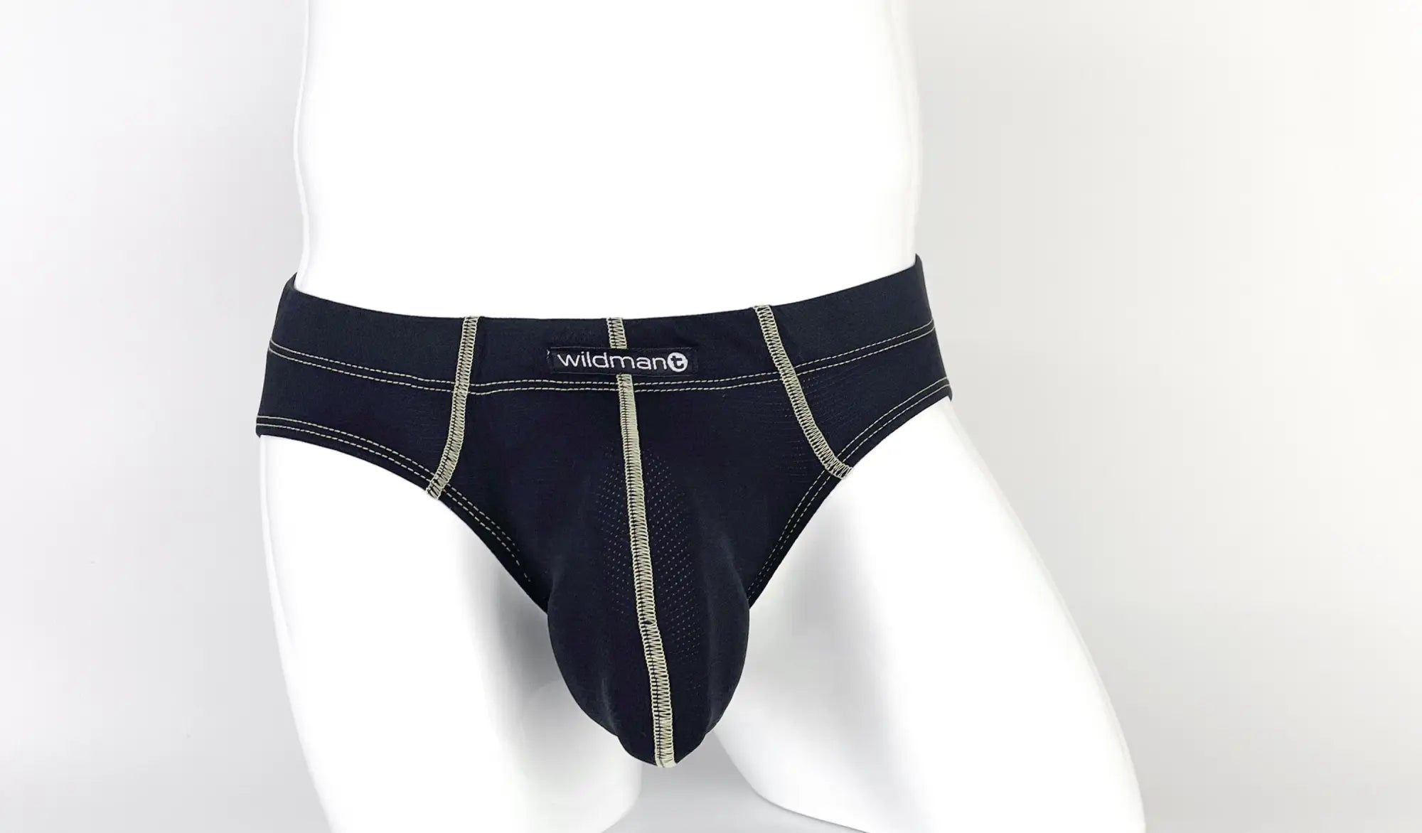 Black pouch brief with visible tan contrast stitching, center seam, and a "wildman" logo tag on a white mannequin.