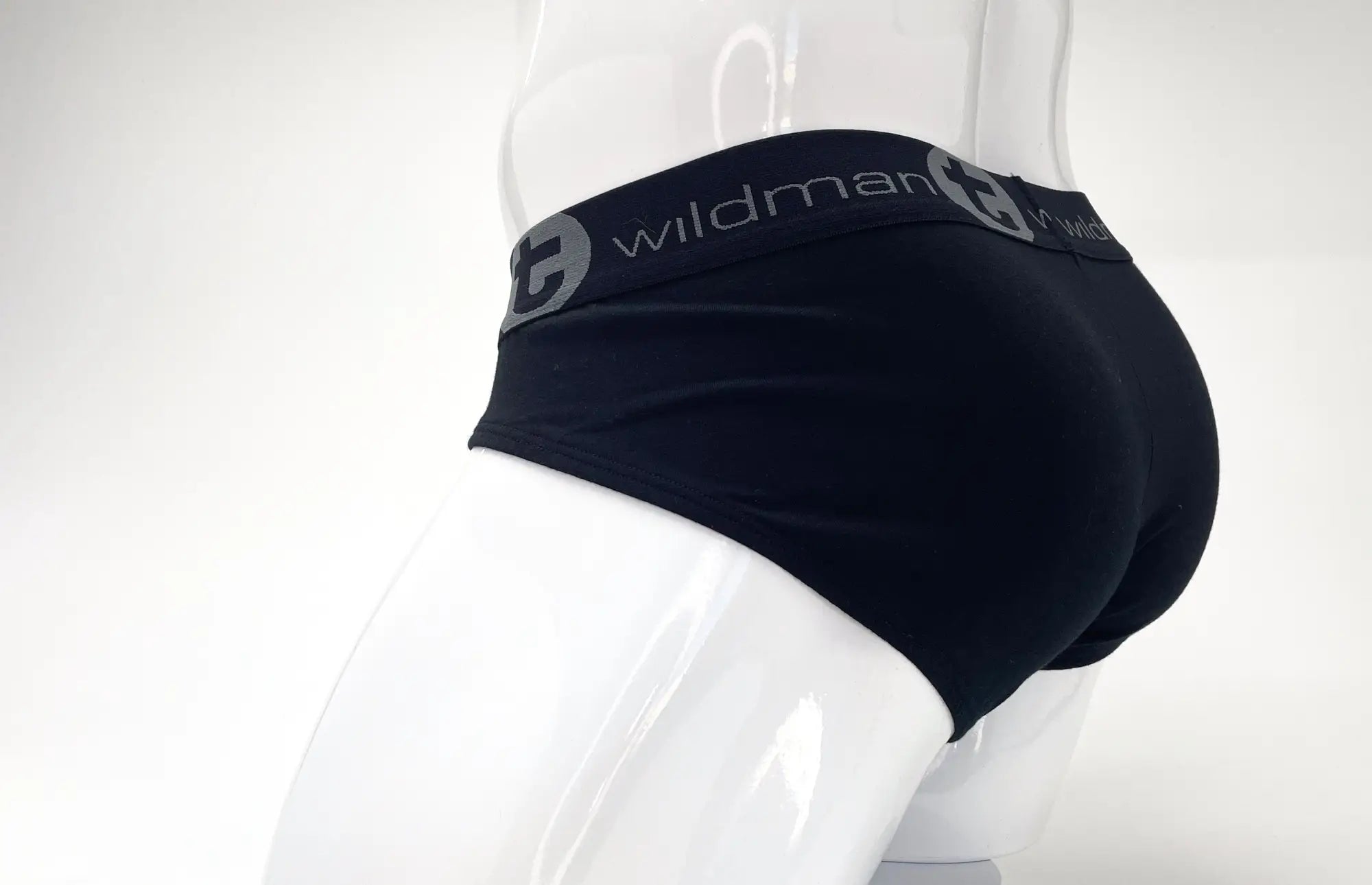 Black stretch cotton brief on a white mannequin, featuring a wide grey elastic waistband with the Wildman T logo.