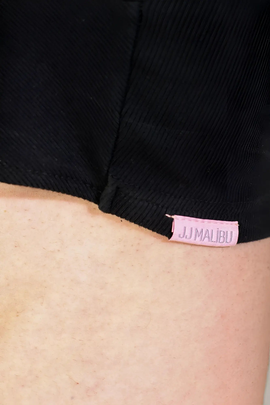 Black ribbed crop tank paired with black denim shorts featuring a pink jj malibu tag in the waistband