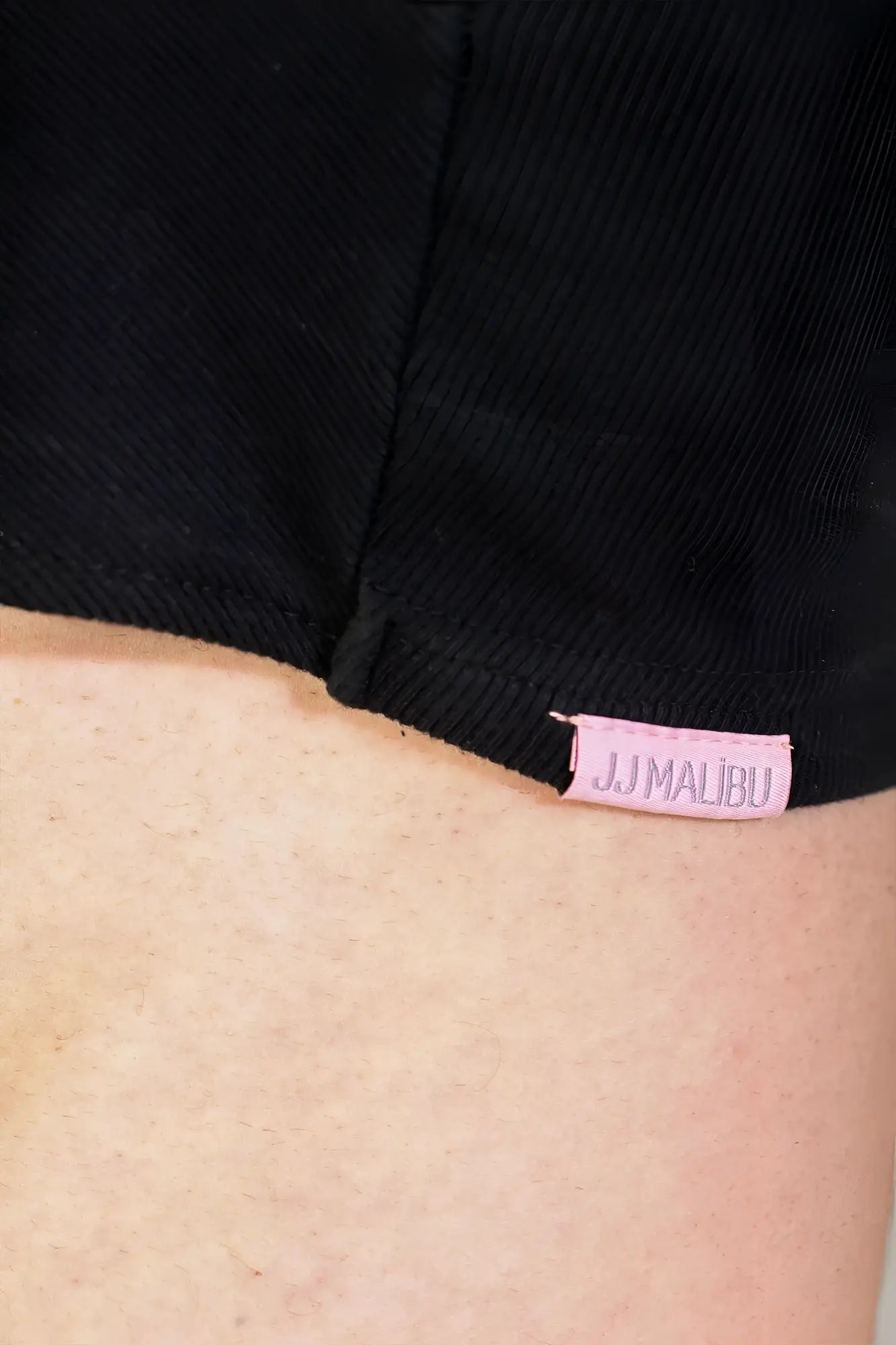 Black ribbed crop tank paired with black denim shorts featuring a pink jj malibu tag in the waistband
