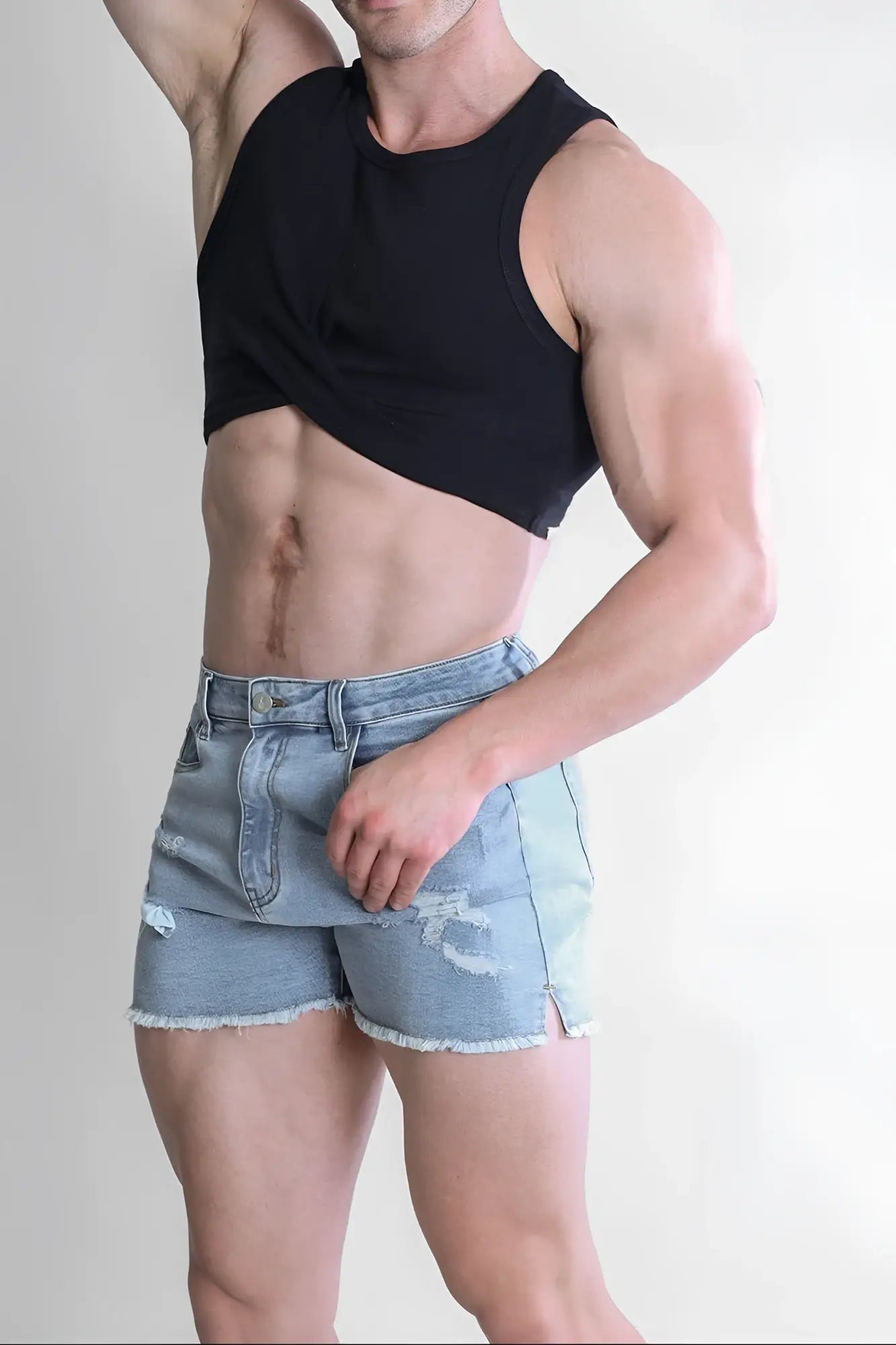 Light-wash denim shorts with frayed hems and distressed patches paired with a black ribbed crop tank