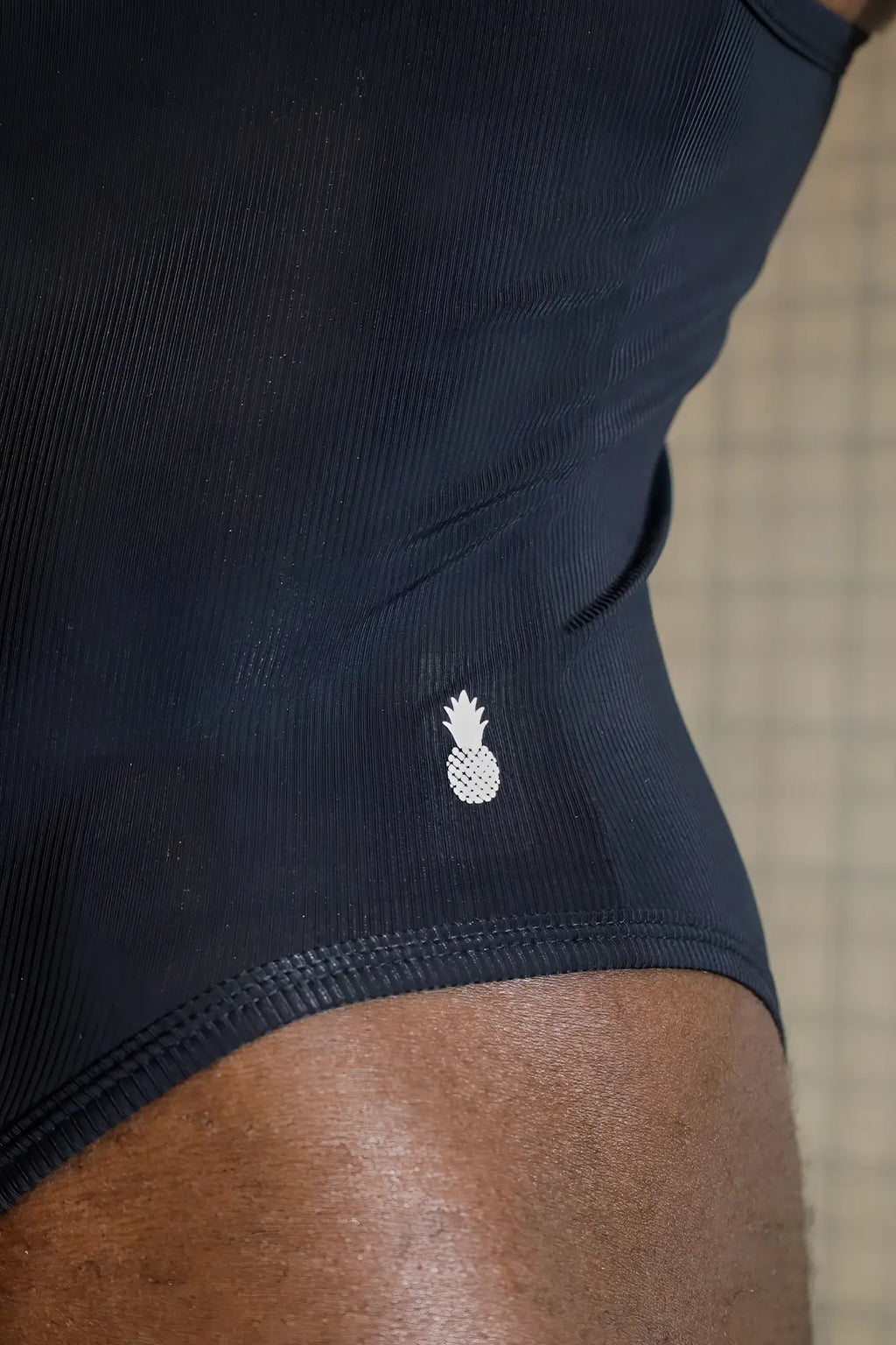 Black ribbed athletic briefs with a small white pineapple logo from the Wrestle Me Bodysuit midnight collection