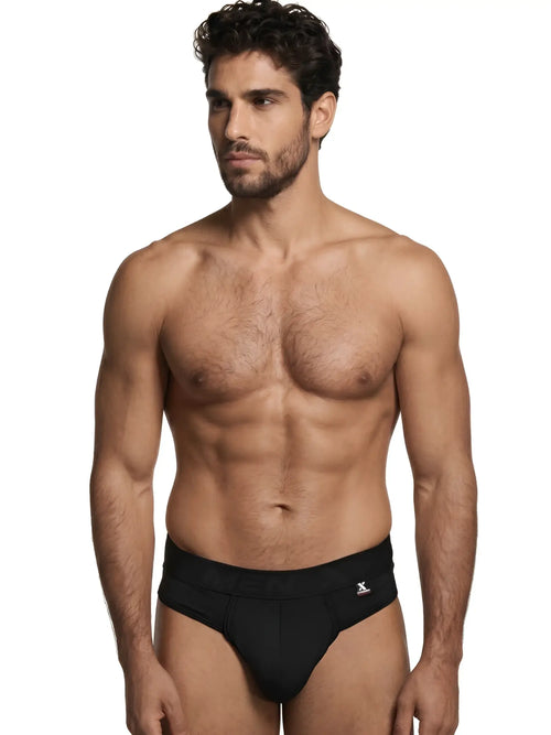 Xtremen men’s black thong with a logo-branded waistband worn by a shirtless man.