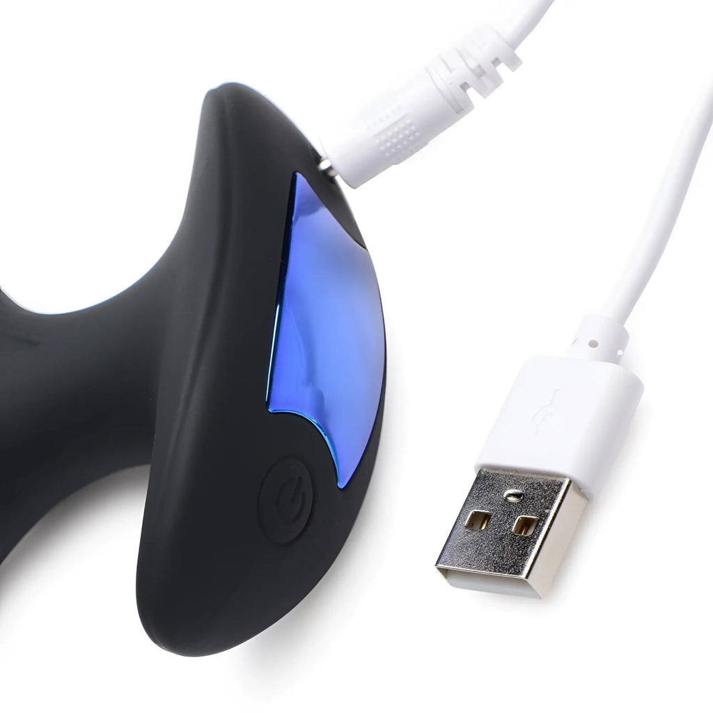 Zeus Electrosex 64X silicone butt plug in black with blue metallic accents and a white USB charging cable.