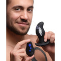A man holding a black Zeus 8X Volt Drop vibrating silicone prostate massager with electric sparks and remote control.