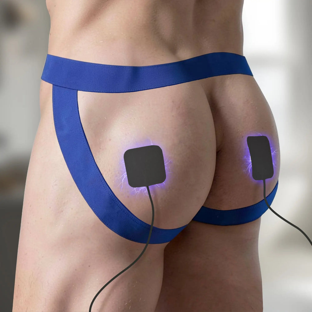 Zeus Electrosex handheld power box with black silicone pads shown on a person wearing a blue jockstrap with electric arcs.
